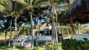 Resort tropical com palmeiras, construção de palha e um caminho de pedra que leva a um edifício.