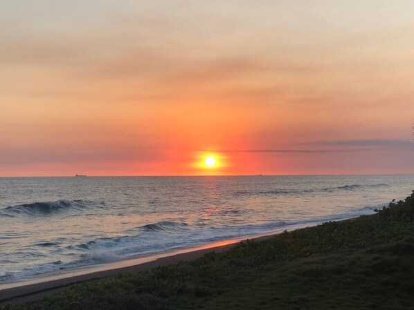 Un coucher de soleil sur l’océan, avec un ciel dégagé et une mer calme.
