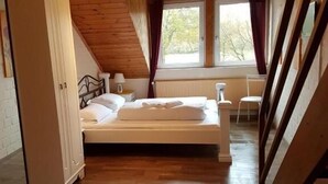 A bedroom with a wooden ceiling, a bed, a window with curtains, and a radiator.