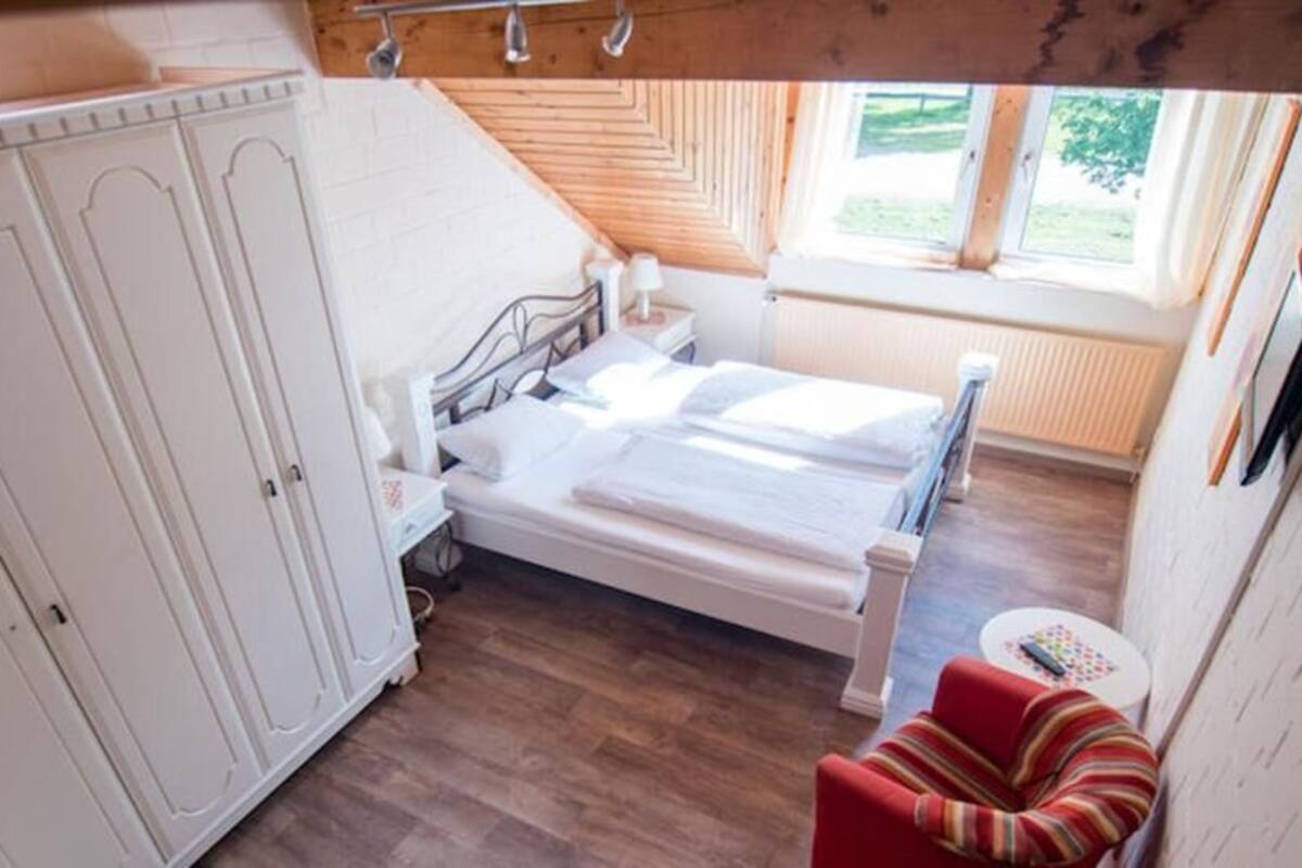 Quarto com cama, guarda-roupa e janela.