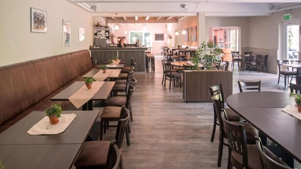 A restaurant with booths and tables, a bar area, and a kitchen in the background.
