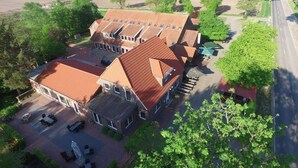 A large, multi-story building with a red-tiled roof, multiple windows, and a spacious patio area with outdoor furniture.