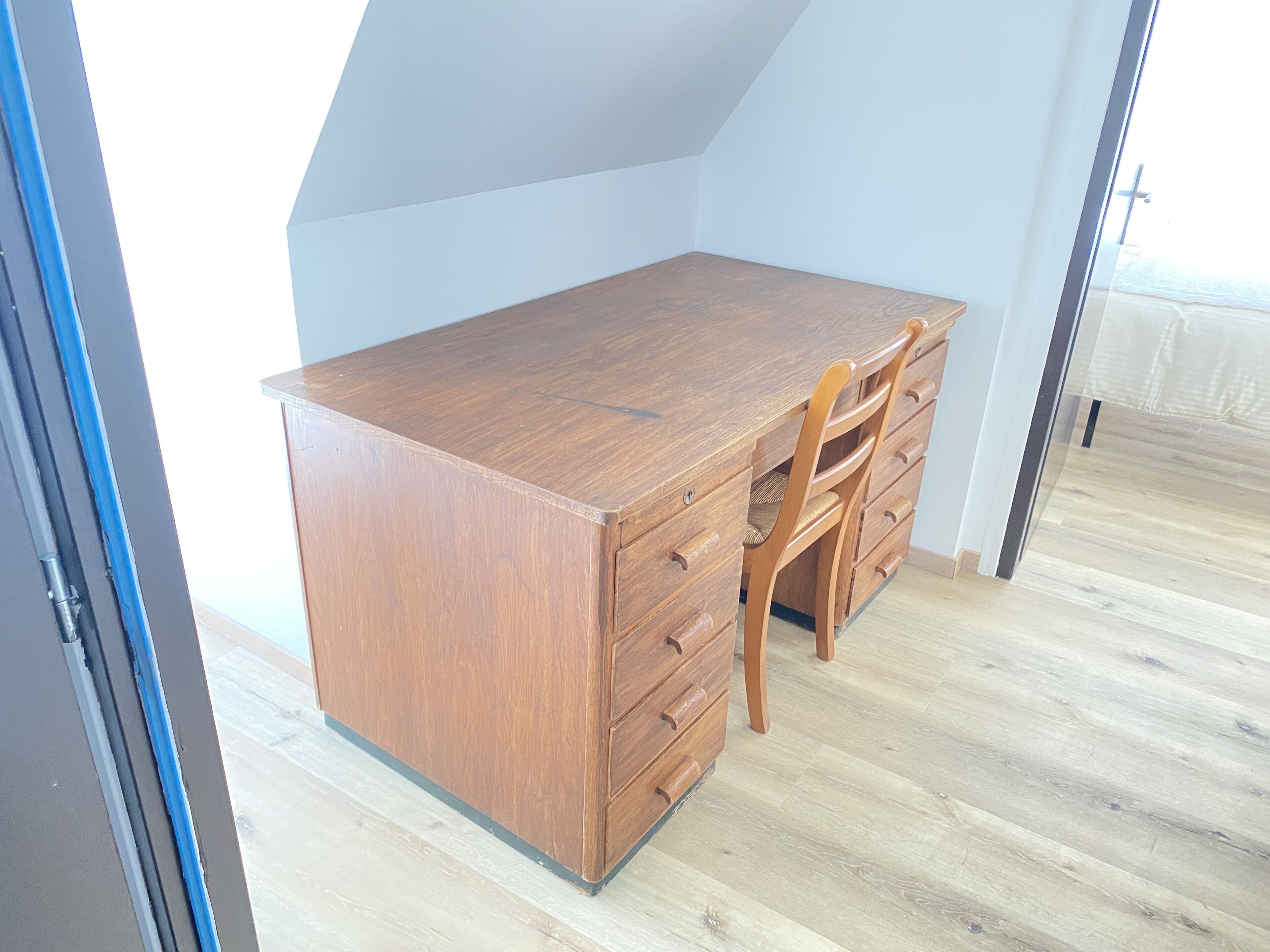 A room with a wooden desk, a chair, and a built-in wardrobe.