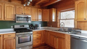 A kitchen with wooden cabinets, stainless steel appliances, a window, and a sink.