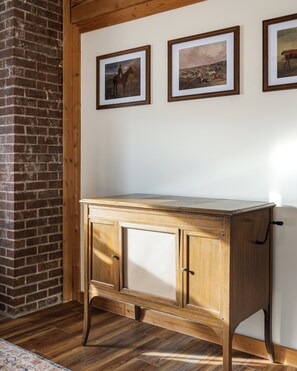A wooden cabinet with two doors and a countertop, positioned against a brick wall with three framed pictures on the wall above. - New Hot Tub - Sweet Pines Cabin - Sleeps up to 8 (Patriot)