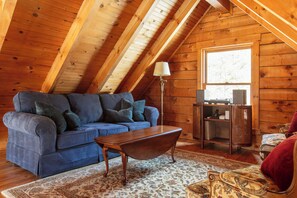 A cozy room with a blue sofa, a wooden coffee table, and a patterned rug. - New Hot Tub - Sweet Pines Cabin - Sleeps up to 8 (Patriot)