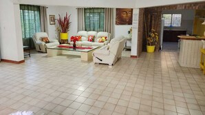 A spacious living room with a large white sofa set, a coffee table, and a dining area with a yellow table. - BOCA DEL PARAISO (Boca Chica)