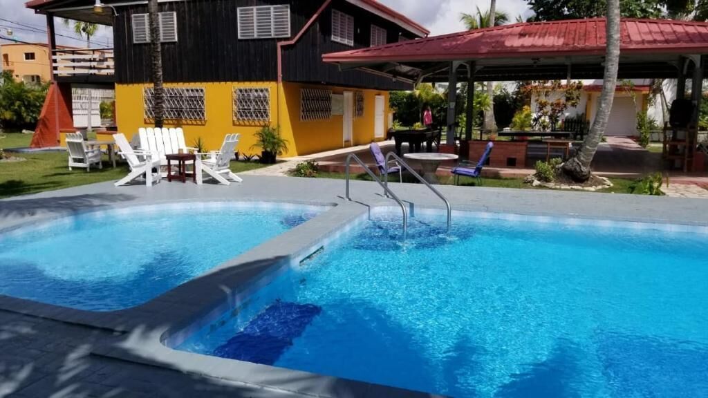 Piscina con sillas de descanso y una zona de estar techada.