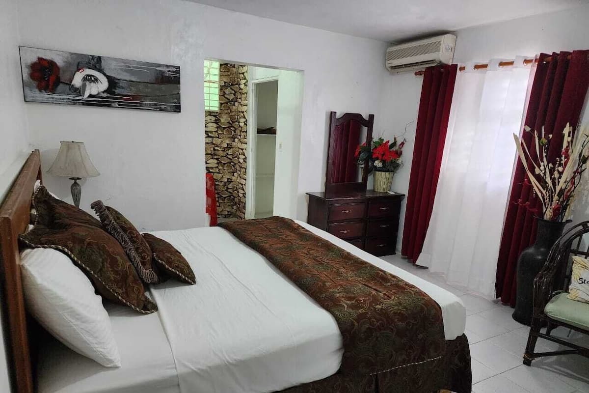 Ein Hotelzimmer mit einem Bett, einem Schminktisch, einem Spiegel und einem Vorhangfenster.