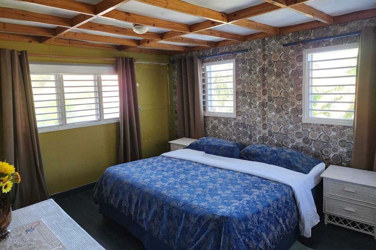 Ein Schlafzimmer mit einem Bett, einem Nachttisch, einem Fenster und einer Steinwand.