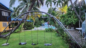 A backyard with a swing set, a pool, and palm trees. - BOCA DEL PARAISO (Boca Chica)