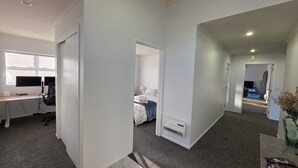 A modern hotel room with a desk, computer, and a bed with a blue blanket. - Huntington Hideaway - Curated Comfort, Hidden in Huntington (Hamilton)