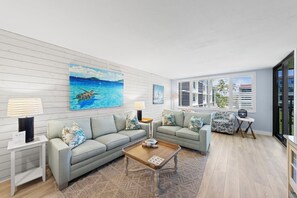 Un salon moderne avec un canapé de couleur claire, une table basse en bois et un grand tableau représentant une tortue de mer.