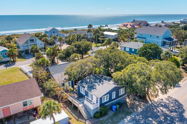A coastal residential area with houses, a beach, and a clear sky.
