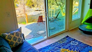 A room with a glass door leading to an outdoor area with a bench and a small water feature. - Retro River House! Waterfront, Firepit, BBQ, Gameroom, 1 min to Sequoia Park.  (Three Rivers)