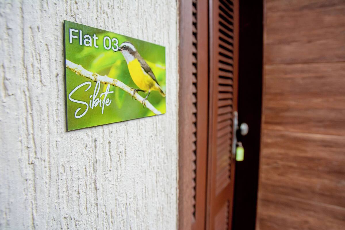 A sign with a bird and the text "Flat 03" and "Sibbe" on a textured wall.