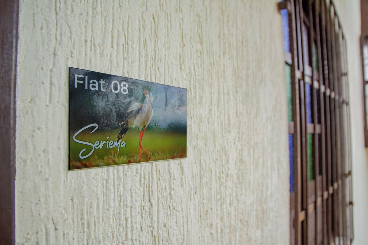 A sign with a bird and the text "Flat 08 Serieia" on a textured wall.