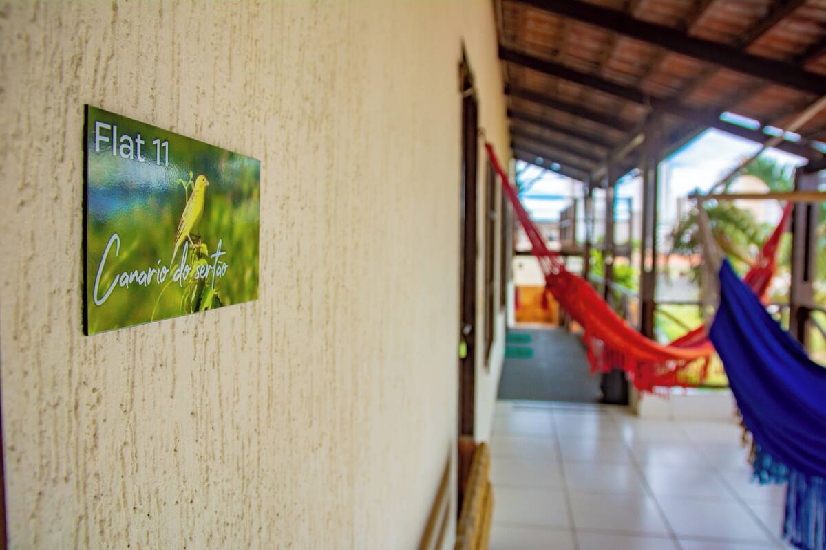 A hallway with a sign reading "Flat 11" and a hammock in the background.
