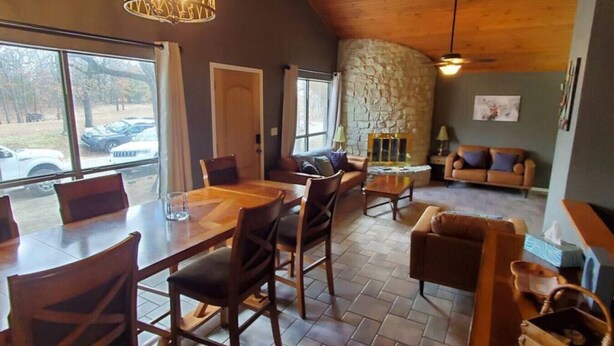 A cozy interior with a dining area, a stone fireplace, and a seating area with a couch and chairs. - Commander`s Cabin - Family Friendly Adventure (Sulphur)