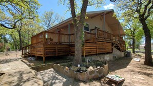 A wooden cabin with a deck and a fire pit area. - Commander`s Cabin - Family Friendly Adventure (Sulphur)
