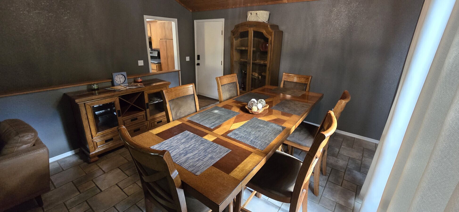 A dining room with a wooden table, chairs, a cabinet, and a mirror.