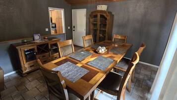 A dining room with a wooden table, chairs, a cabinet, and a mirror.