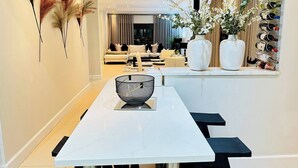 A modern dining area with a white table, black chairs, and a decorative bowl centerpiece. - Staycation With Back Up Power (Germiston)