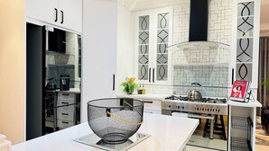 A modern kitchen with white cabinetry, a gas stove, and a decorative bowl on the counter. - Staycation With Back Up Power (Germiston)