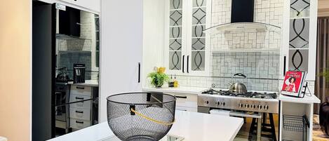 A modern kitchen with white cabinetry, a gas stove, and a decorative bowl on the counter.