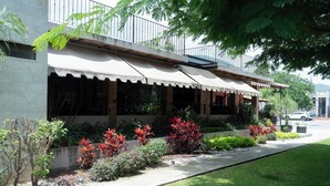A building with a covered outdoor seating area, a paved walkway, and a variety of plants. - La Joya del Lago (Chapala)