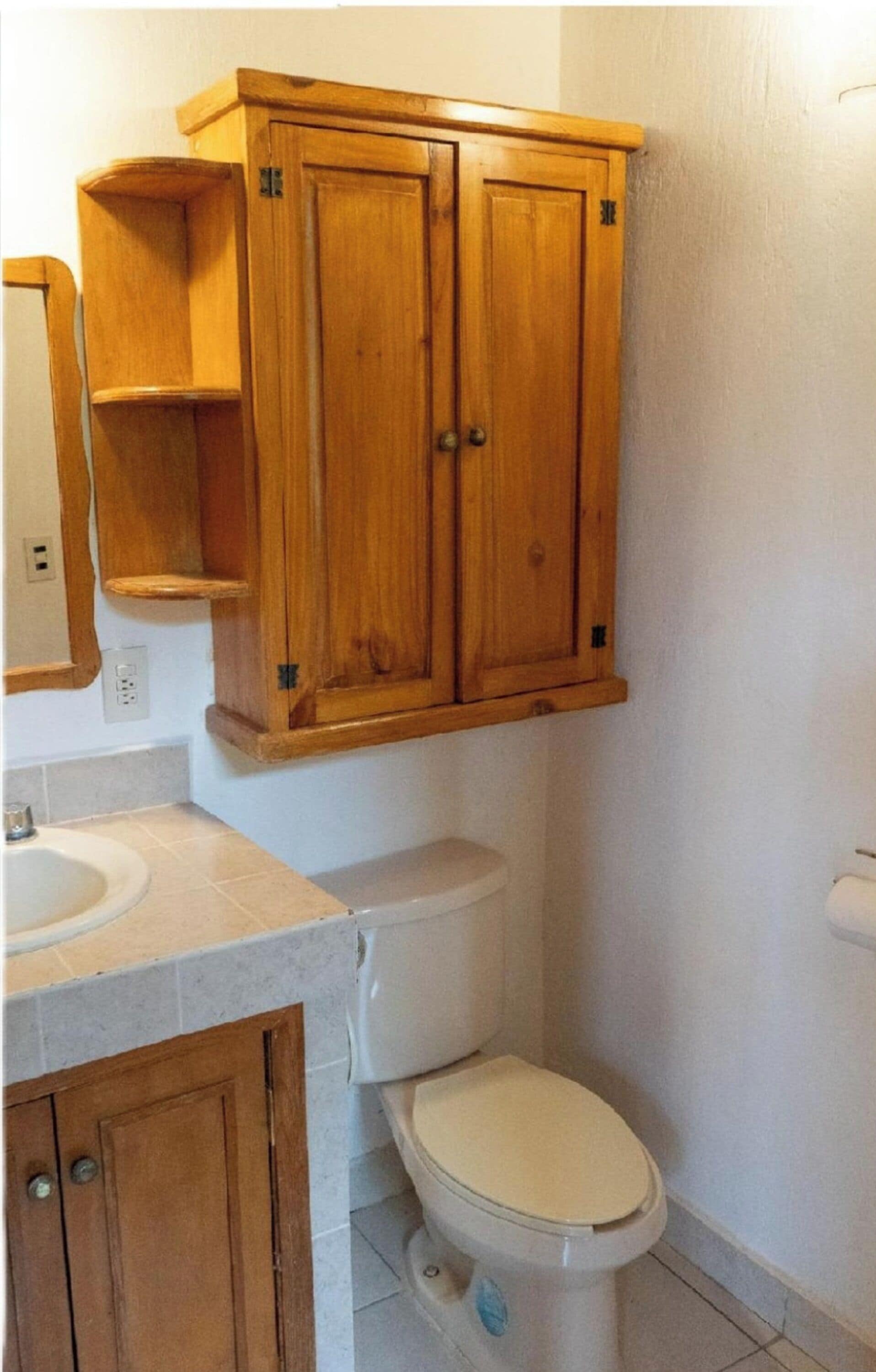 Un baño con armarios de madera, inodoro y lavabo.