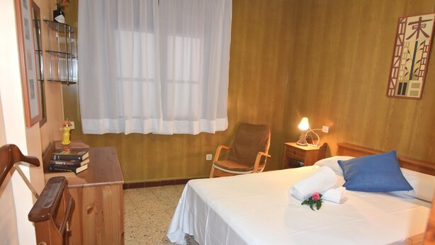 Ett hotellrum med en säng, en stol, ett skrivbord och ett nattduksbord.