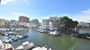 A marina with various boats docked, surrounded by buildings and trees.