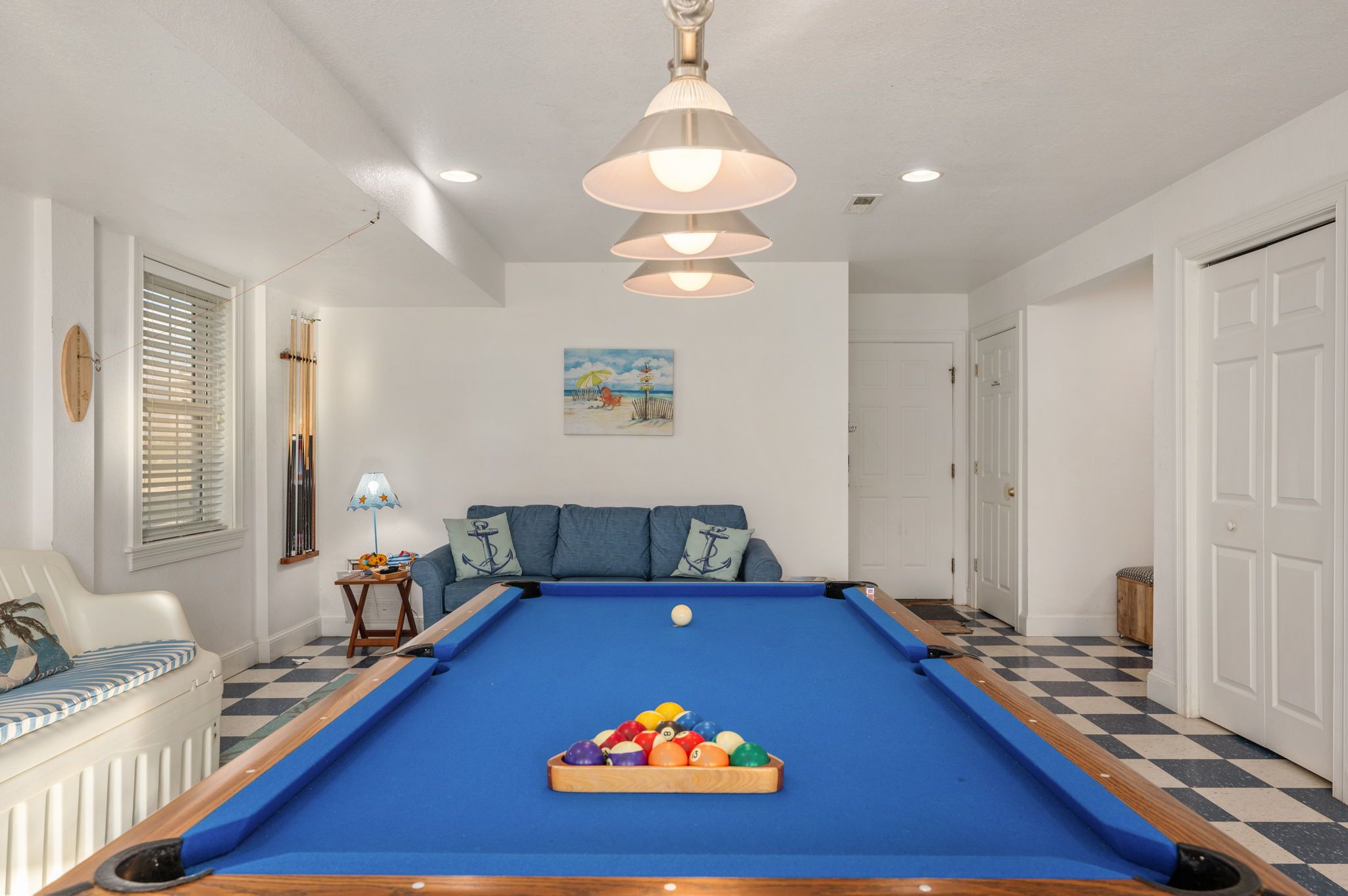 Ein Billardtisch mit Kugeln, eine Couch, eine Lampe und ein Gemälde an der Wand.