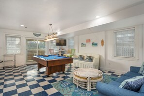A pool table in a room with a checkered floor, a sofa, and a television.
