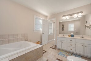 Ein Badezimmer mit Badewanne, einem Doppelwaschtisch mit Spiegel und Toilette.