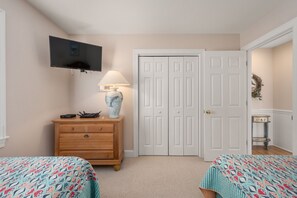 A bedroom with two beds, a dresser, a TV, and a door.