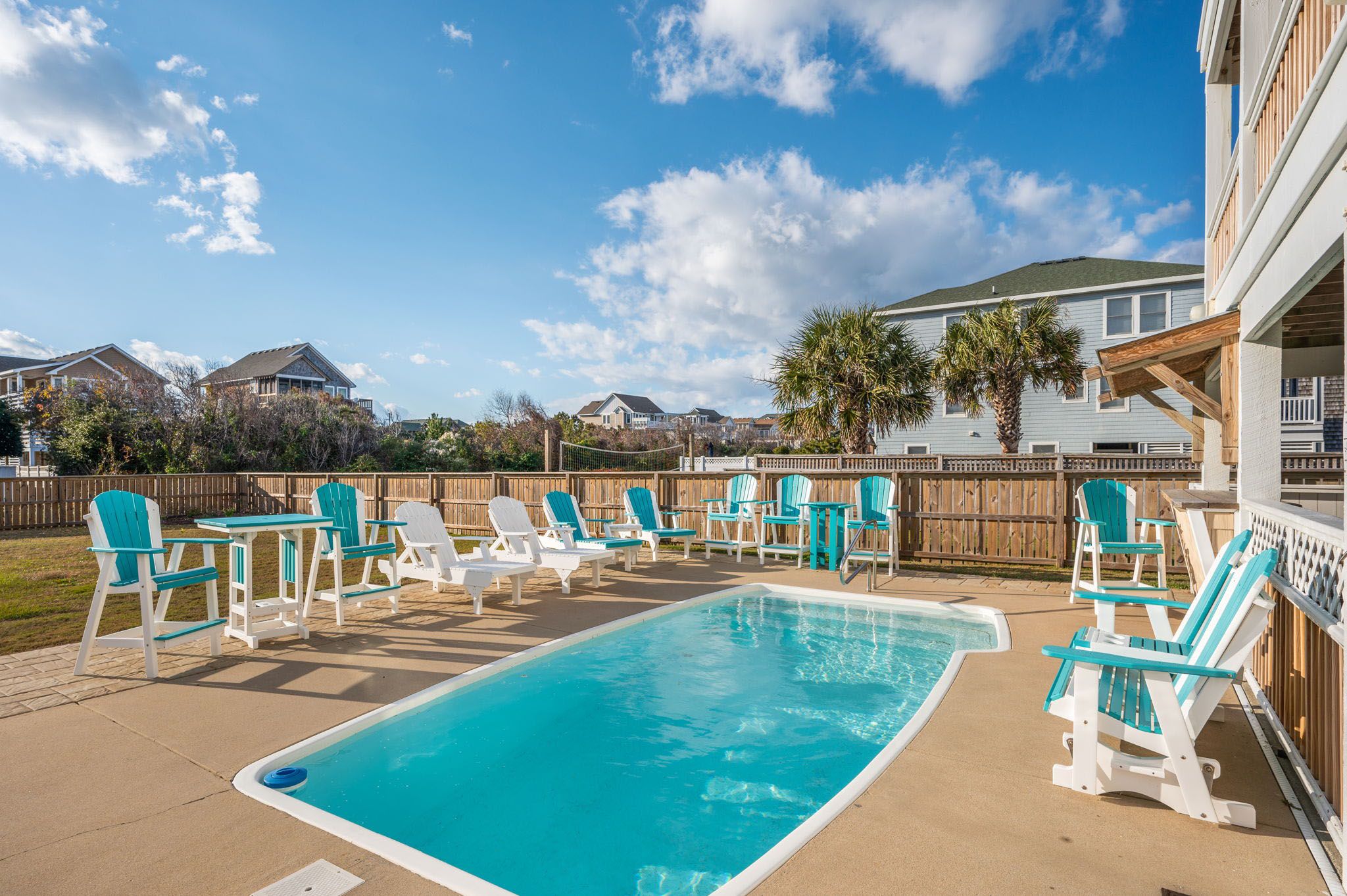A swimming pool with lounge chairs and a wooden deck.