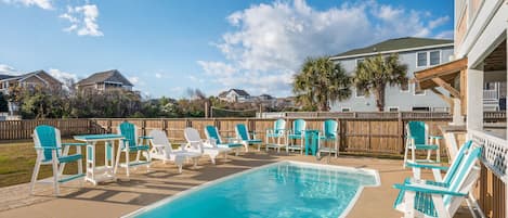 A swimming pool with lounge chairs and a wooden deck.