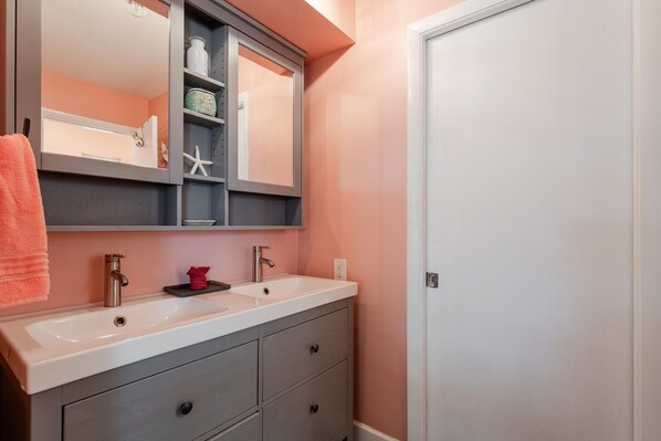 Une salle de bain avec deux lavabos, un grand miroir et un porte-serviettes.