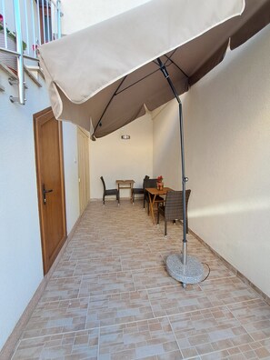 Enjoy a patio with a table and chairs, perfect for relaxing under the shade of a large umbrella.