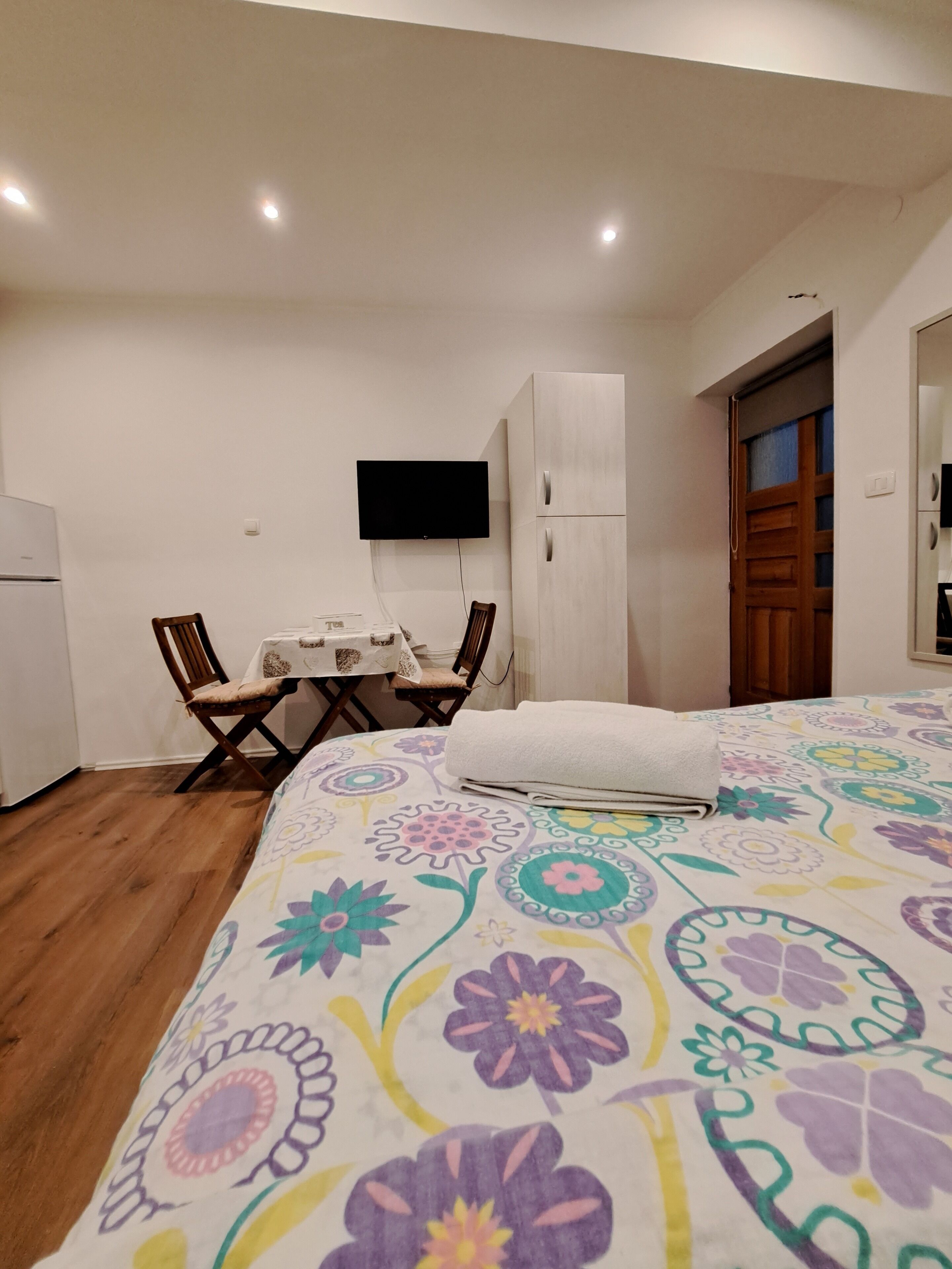A bedroom with a bed, a desk, a chair, a television, and a wardrobe.