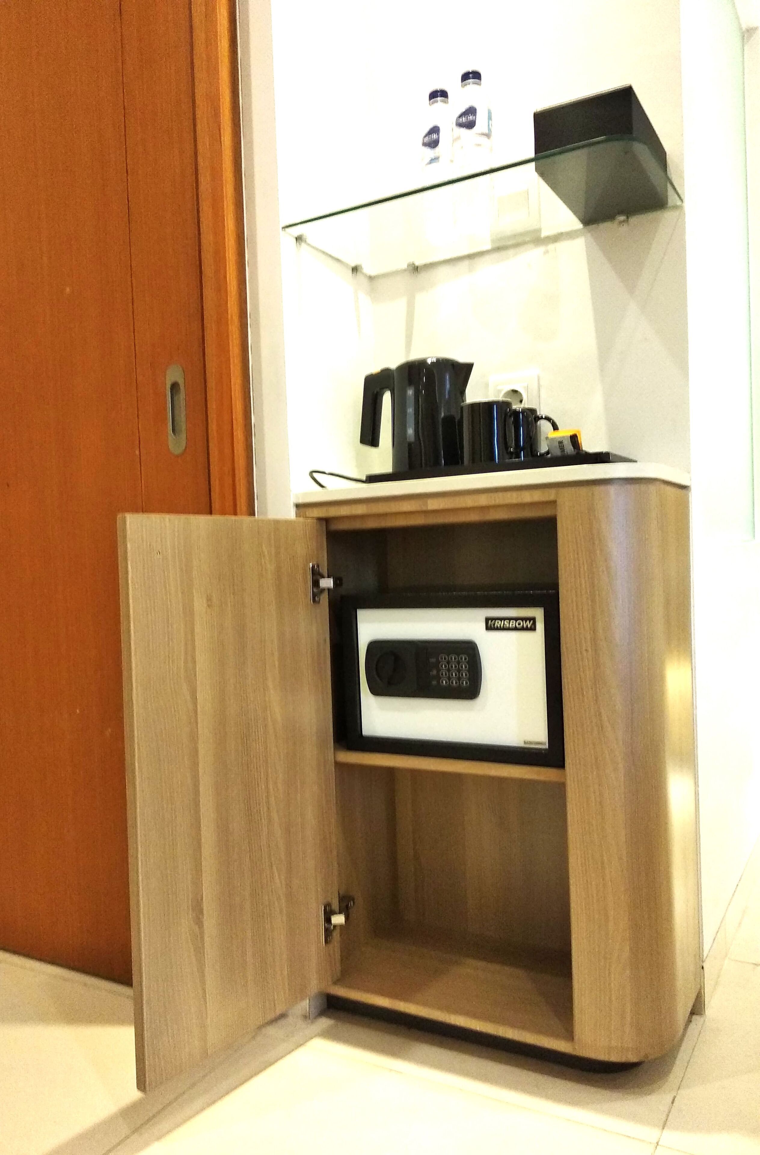 A wooden cabinet with a built-in electronic device, a glass shelf above it, and a wooden door.