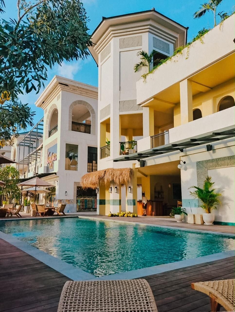 Un resort con piscina, area salotto all'aperto e un edificio a più piani con balconi.