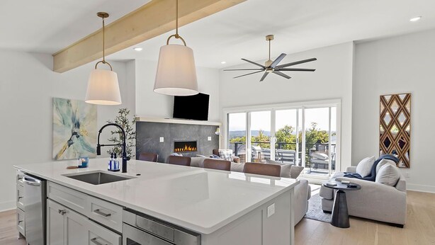A modern kitchen with a large island, built-in oven, and a dining area with a sofa and table.