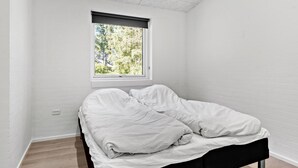 Una camera piccola con un letto singolo e una finestra su un paesaggio verde.