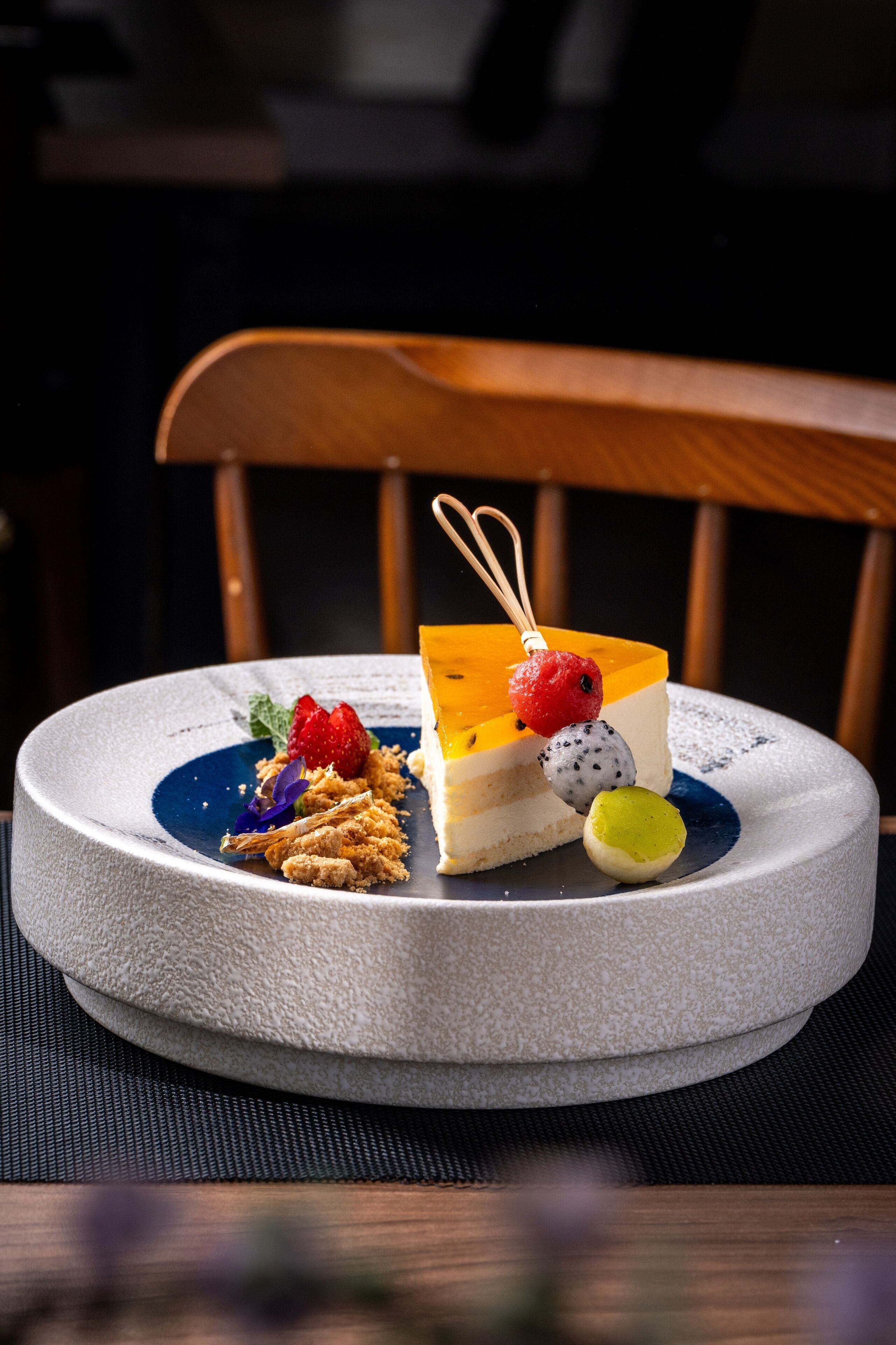 A dessert on a round ceramic plate with a wooden chair in the background.