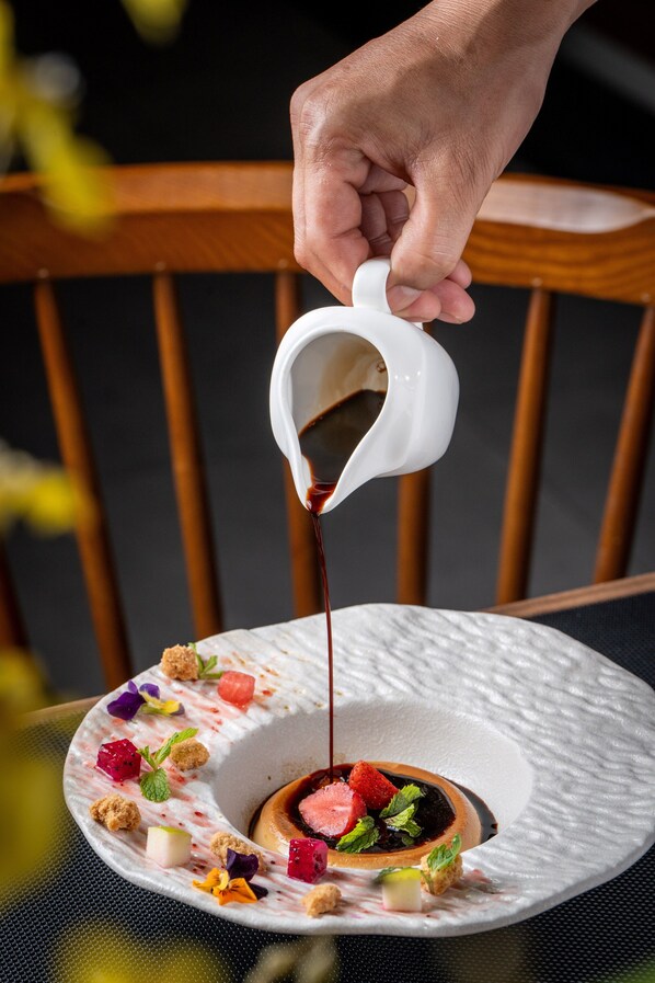 Postre siendo servido de una jarra sobre un plato con diferentes adornos.