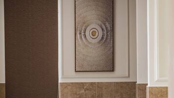 A modern bathroom with a rectangular bathtub, a wall-mounted towel rack, and a decorative wall piece.