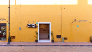 En gul byggnad med en skylt som visar texten ”Hostal Ixchel” och en dörr med samma text.